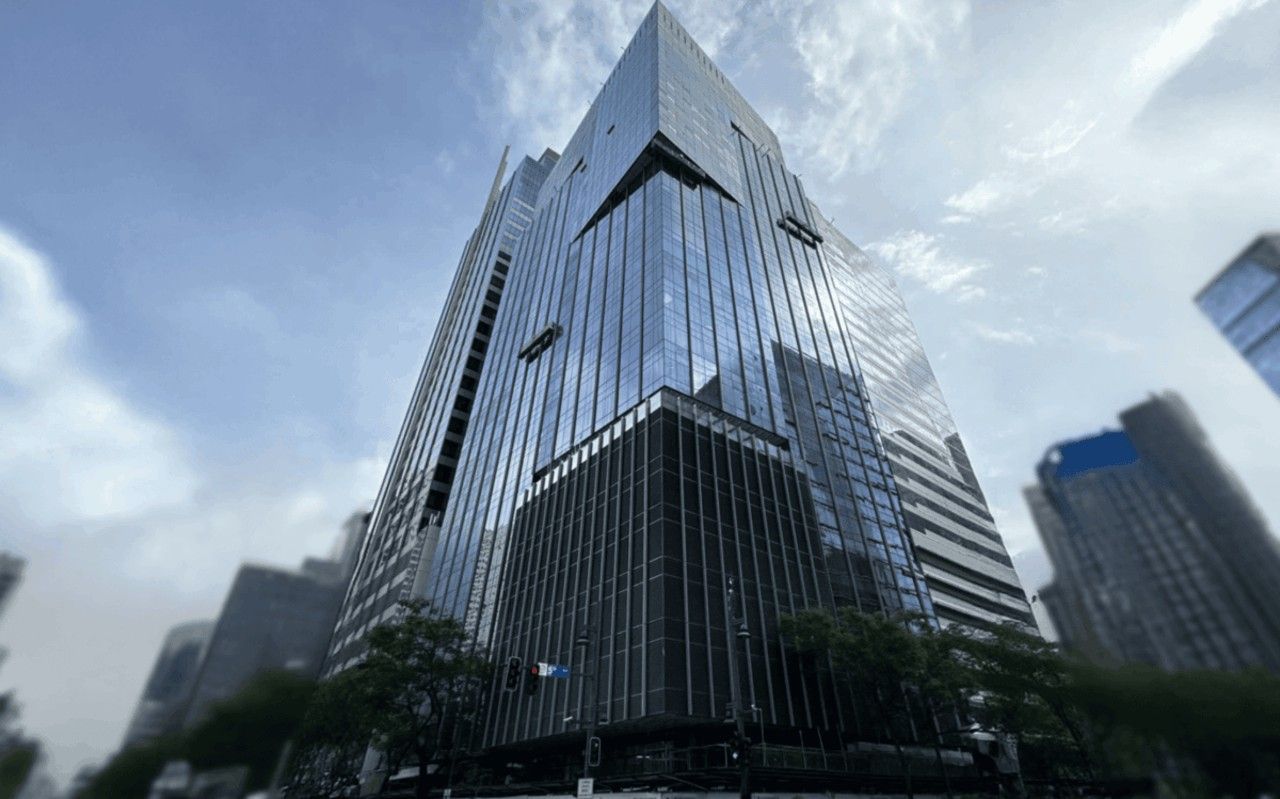 Pioneer House in Bonifacio Global City, its dark glazed tower rising against a bright sky.